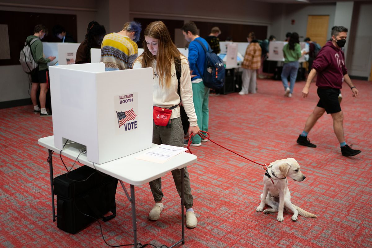 A person with a dog on a leash casts their votes at a polling place in a student center at Ohio State University in Columbus, Ohio, on November 8, 2022.
