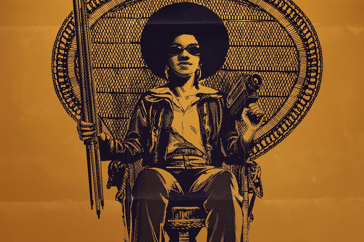 The poster of the film, featuring a Black woman with 1970s-style hair and wearing shades while sitting in a chair.