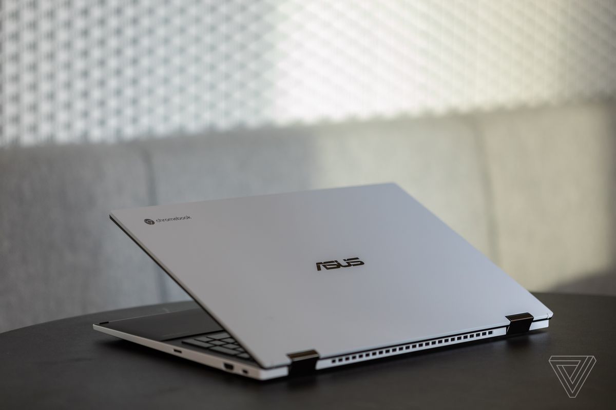 The Asus Chromebook Flip CX5 half open, seen from the back, angled to the left, with a white textured wall in the background.
