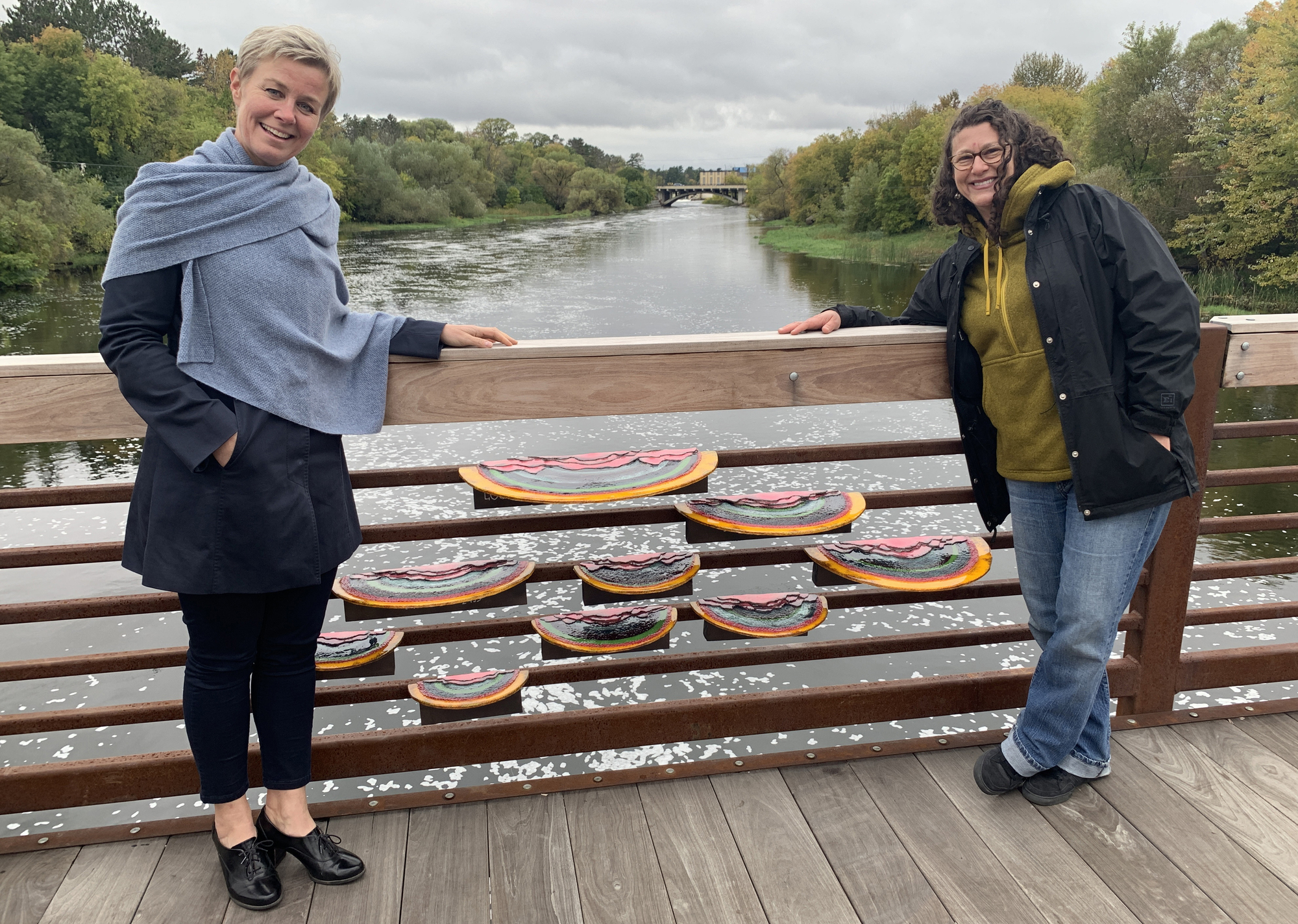 Public art, including this temporary sculpture of colorful fungi on a bridge spanning the Mississippi River, has been popping up around Grand Rapids this year, thanks to the city’s Arts and Culture Commission. At left is Sonja Merrild, commission chair, with artist Nicole Camene.