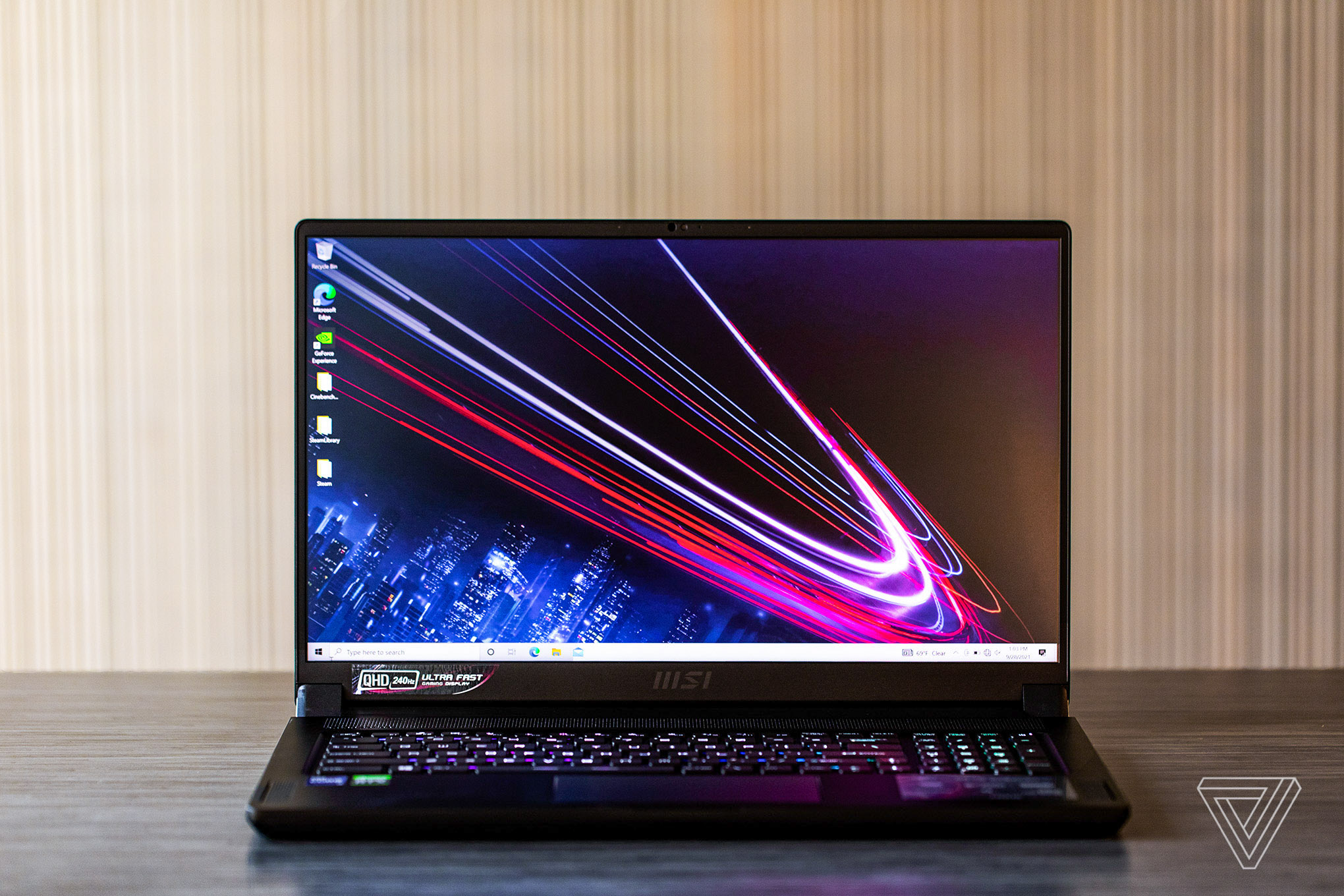 The MSI GS76 Stealth on a table, open. The screen displays a blue and dark red background.