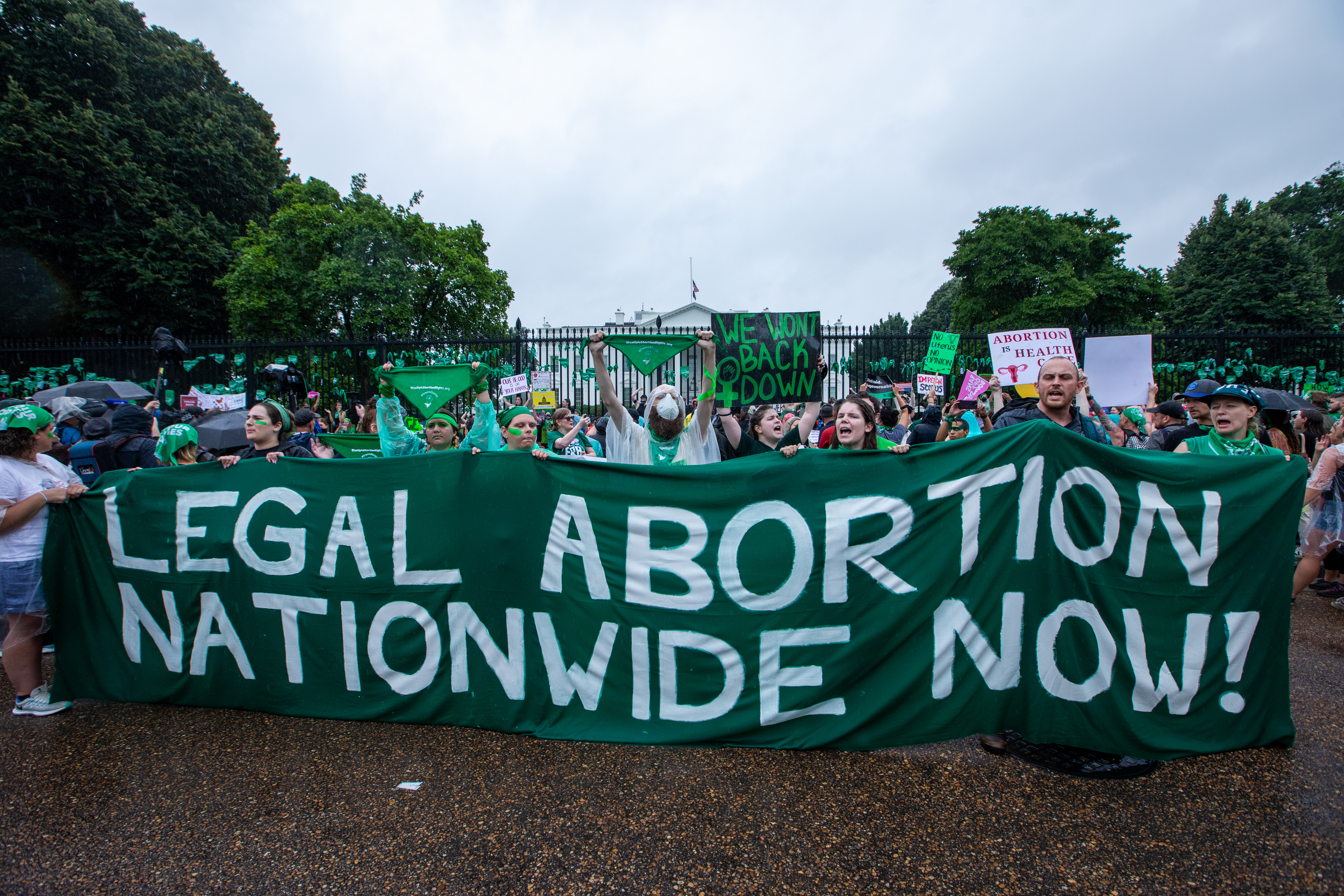 A crowd of people hold up a banner that reads, “Legal abortion nationwide now!”