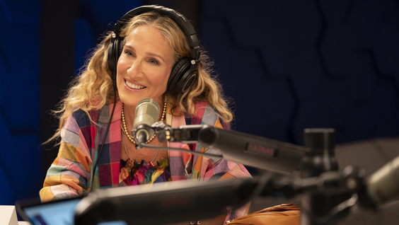 Sarah Jessica Parker as Carrie Bradshaw wearing headphones and sitting at a recording microphone.