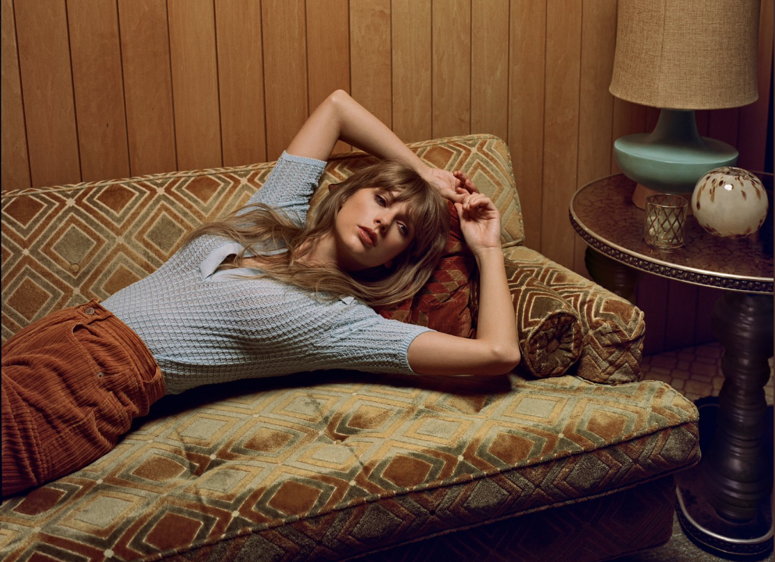Taylor Swift reclines on a couch.