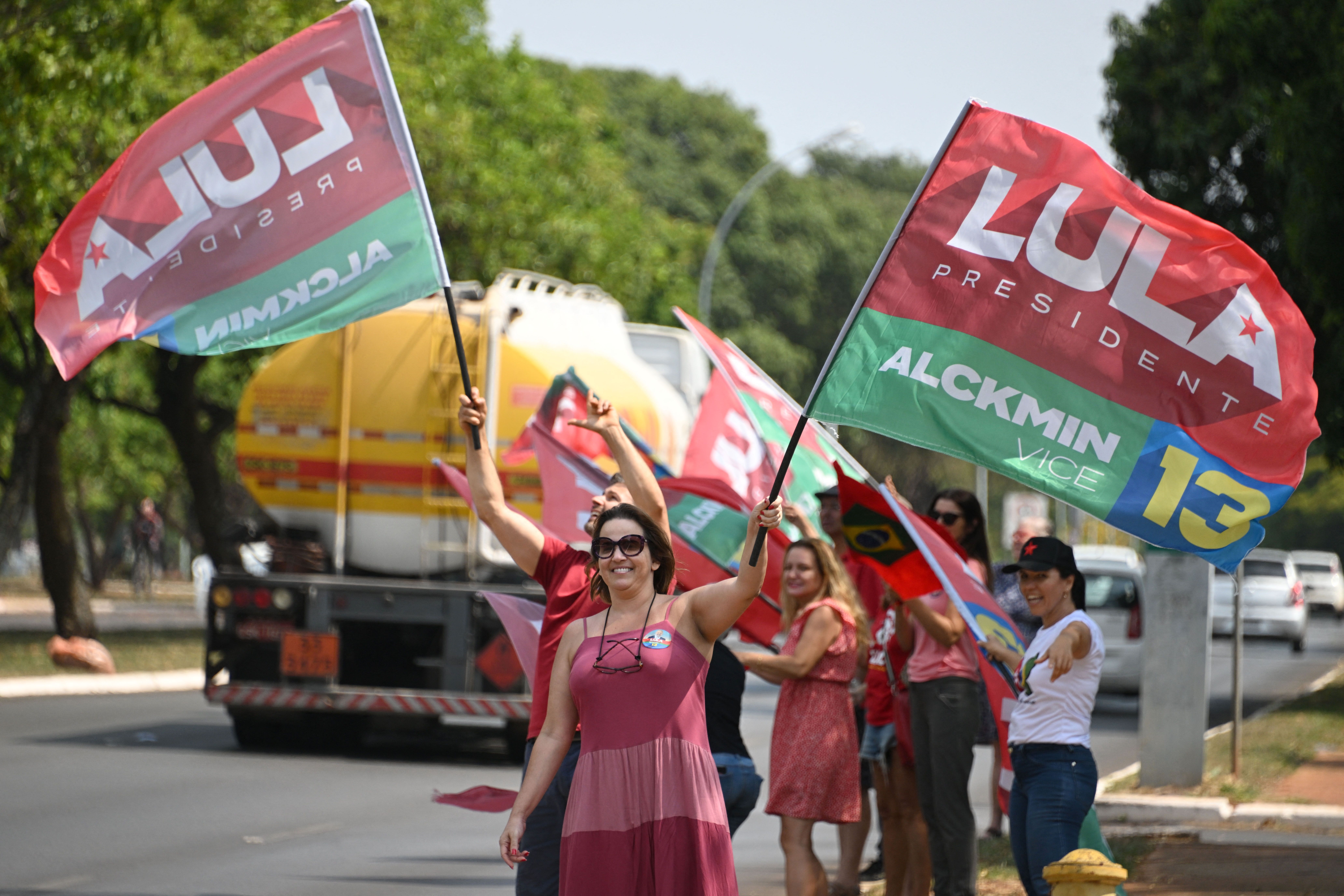 Brazilian voters wave red, green, and blue flags supporting presidential candidate Luiz Inácio Lula da Silva in an upcoming runoff election.