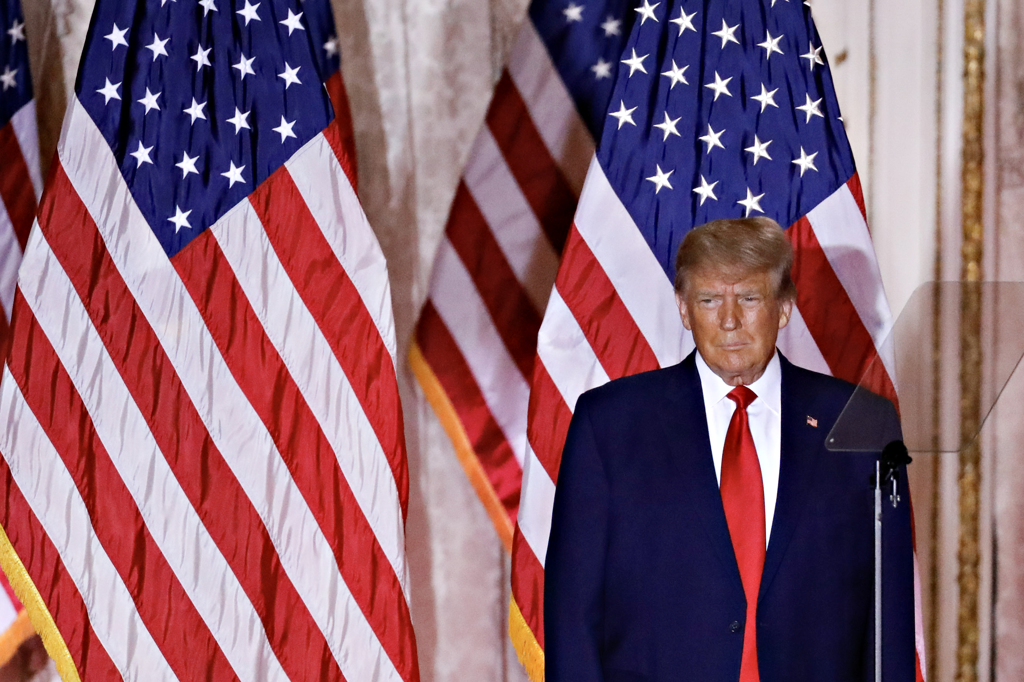 Donald Trump standing onstage in front of American flags.