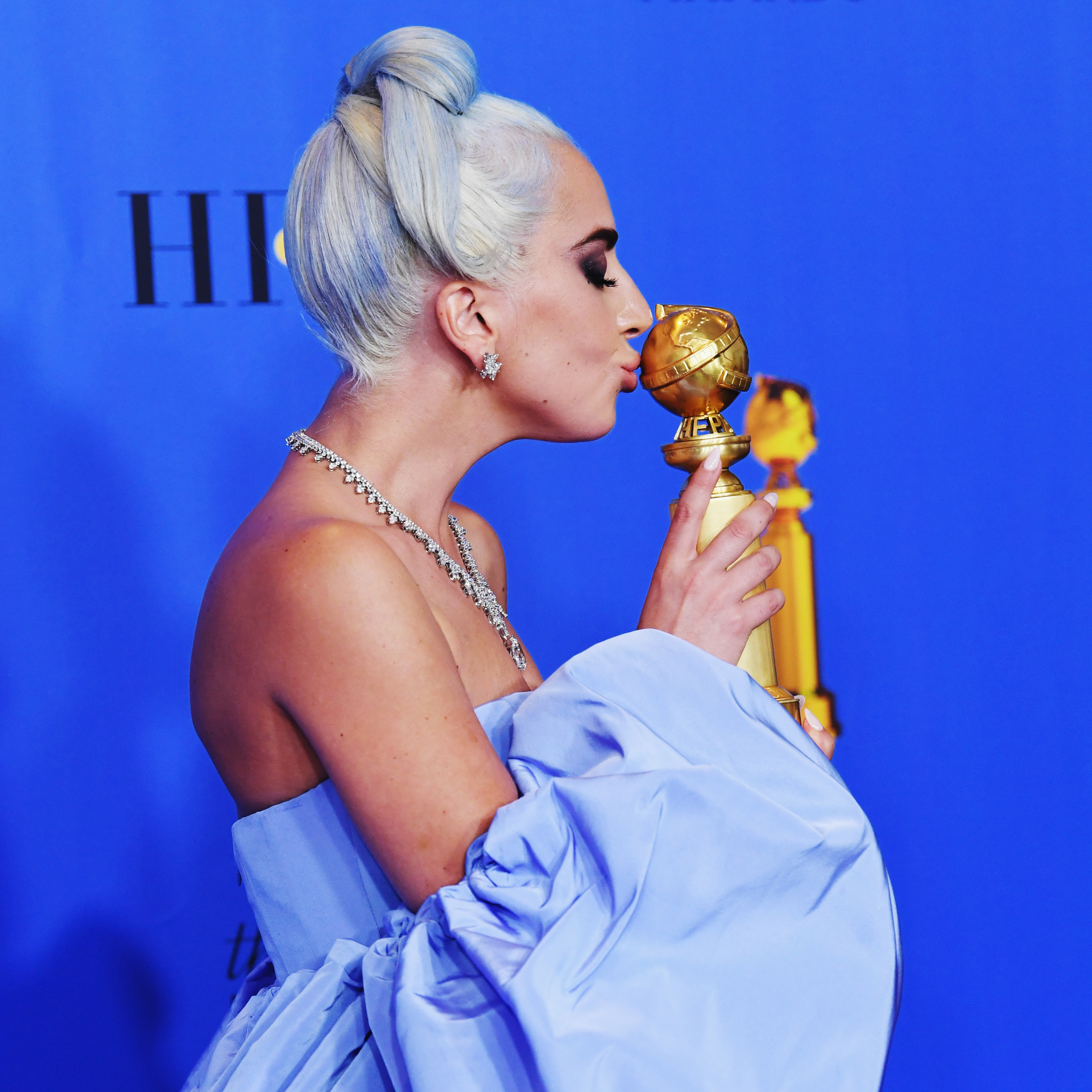 Lady Gaga in profile, kissing her Golden Globe statuette.