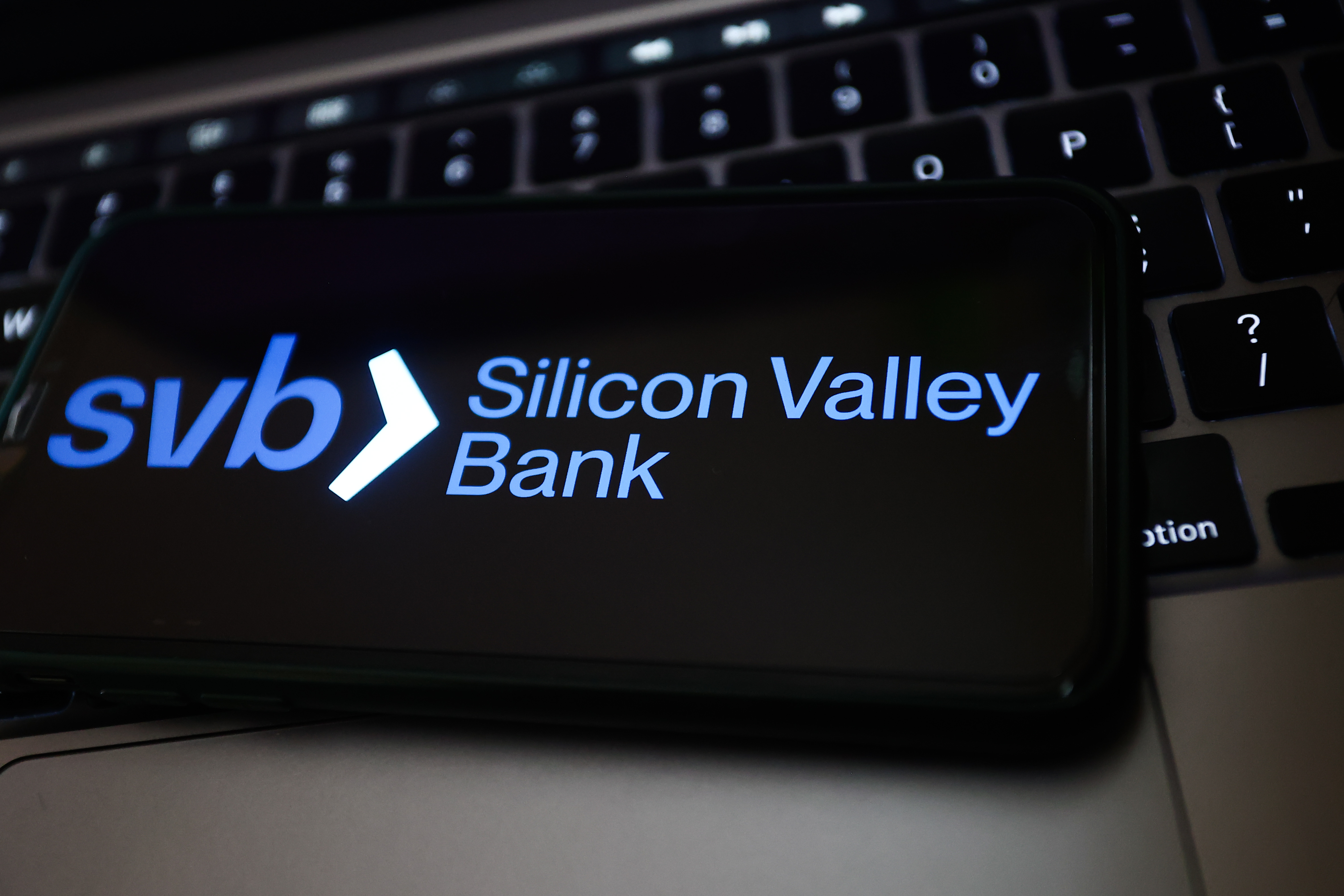 Silicon Valley Bank logo displayed on a phone screen and a laptop keyboard