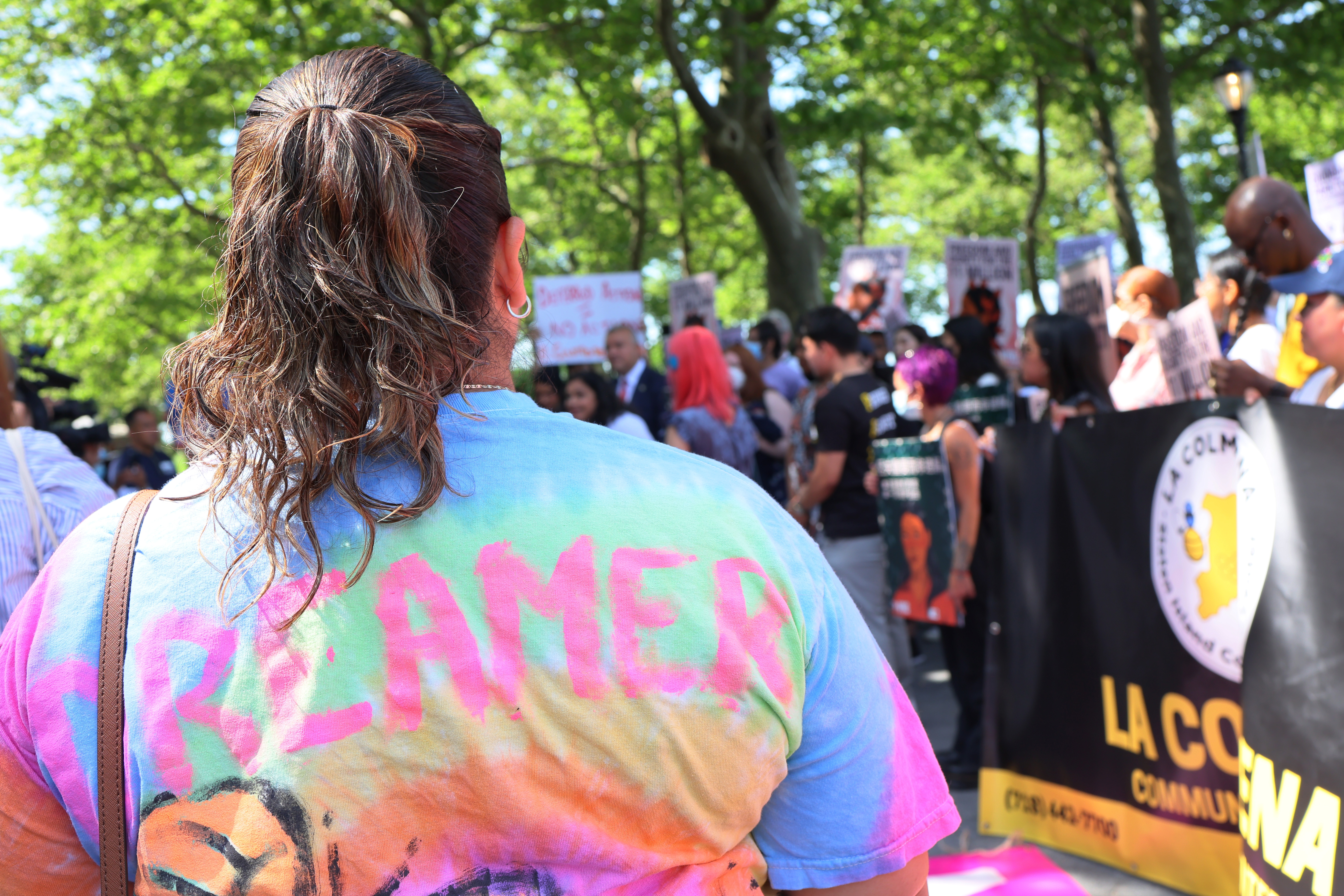 A person at an outdoor rally wearing a shirt that says “Dreamer” across the back.