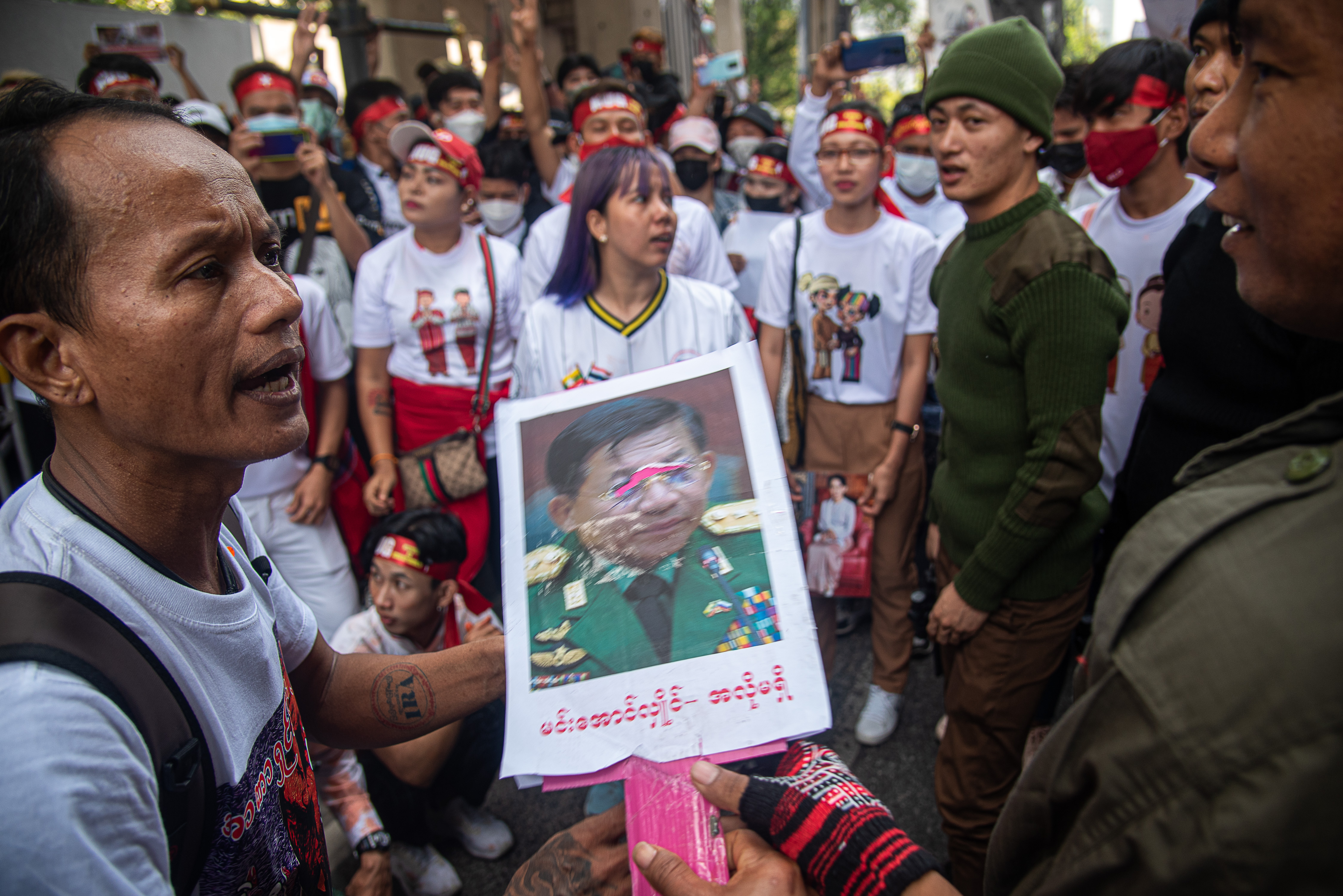 Protesters hold a portrait of Min Aung Hlaing during a demonstration while wearing matching white and red outfits