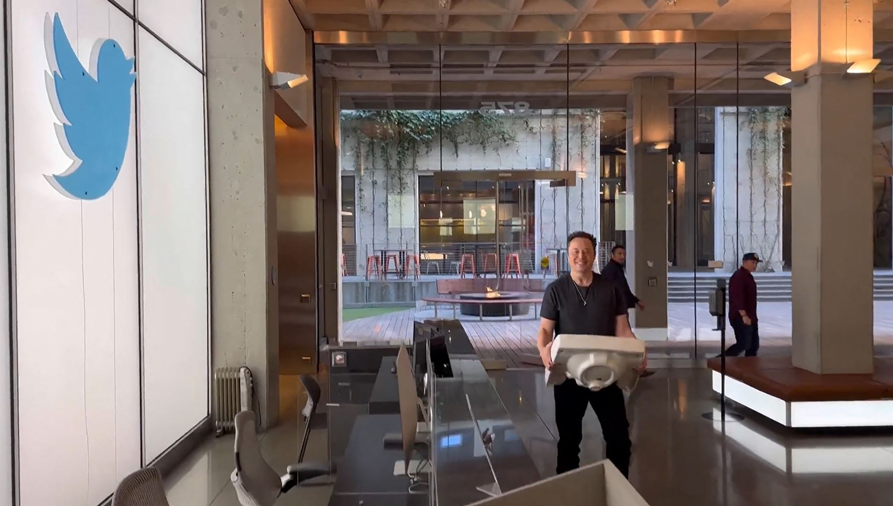 Elon Musk in the Twitter headquarters holding a sink.