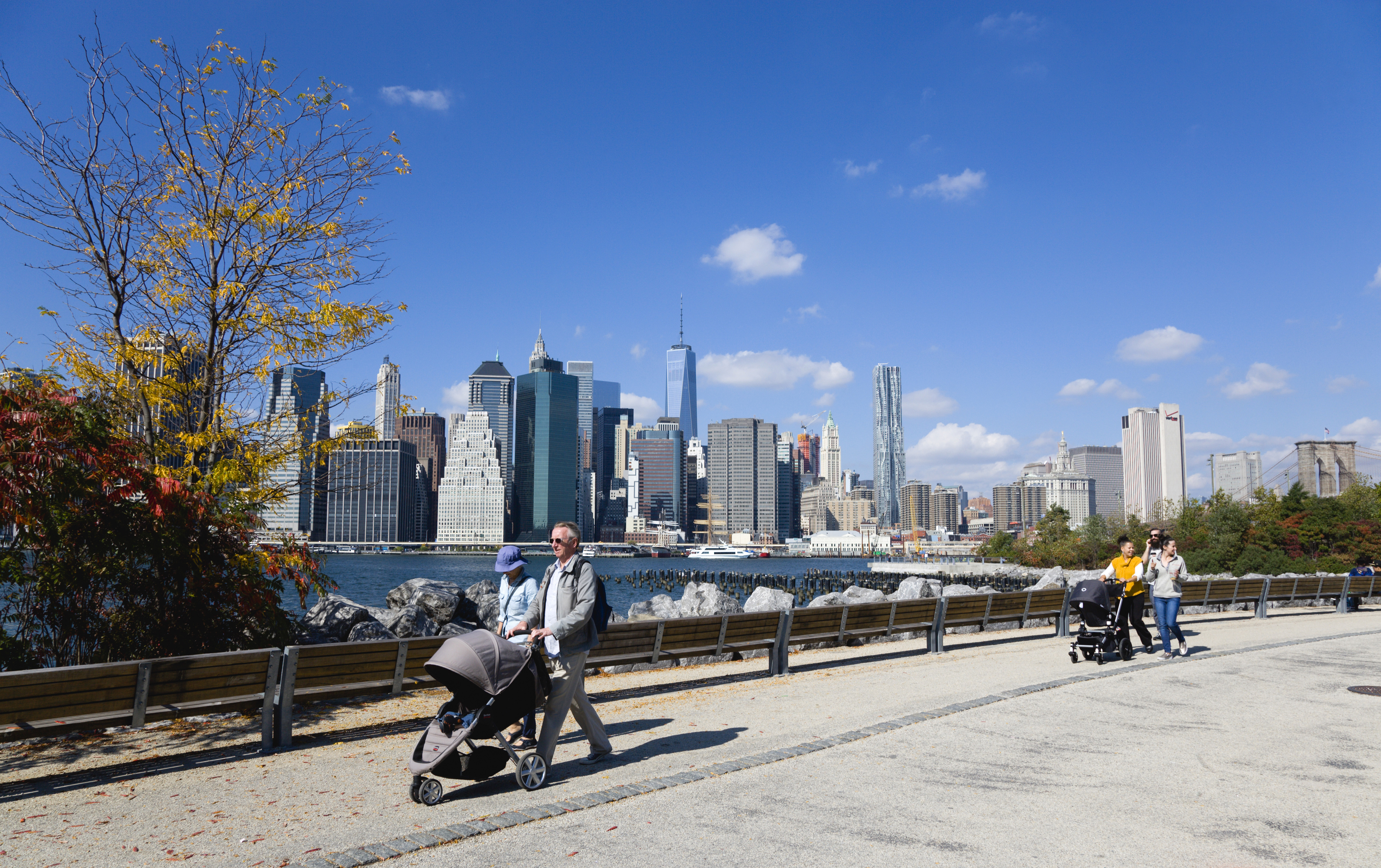 The New York City skyline with pedestrians and strollers in the foreground.