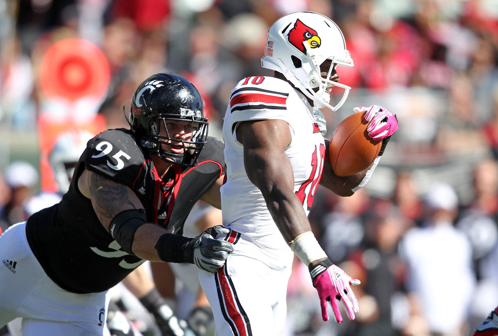 CINCINNATI, OH - OCTOBER 15: Derek Wolfe #95 of the Cincinnati Bearcats tackles Dominique Brown #10 of the Louisville Cardinals during the game at Paul Brown Stadium on October 15, 2011 in Cincinnati, Ohio.  (Photo by Andy Lyons/Getty Images)