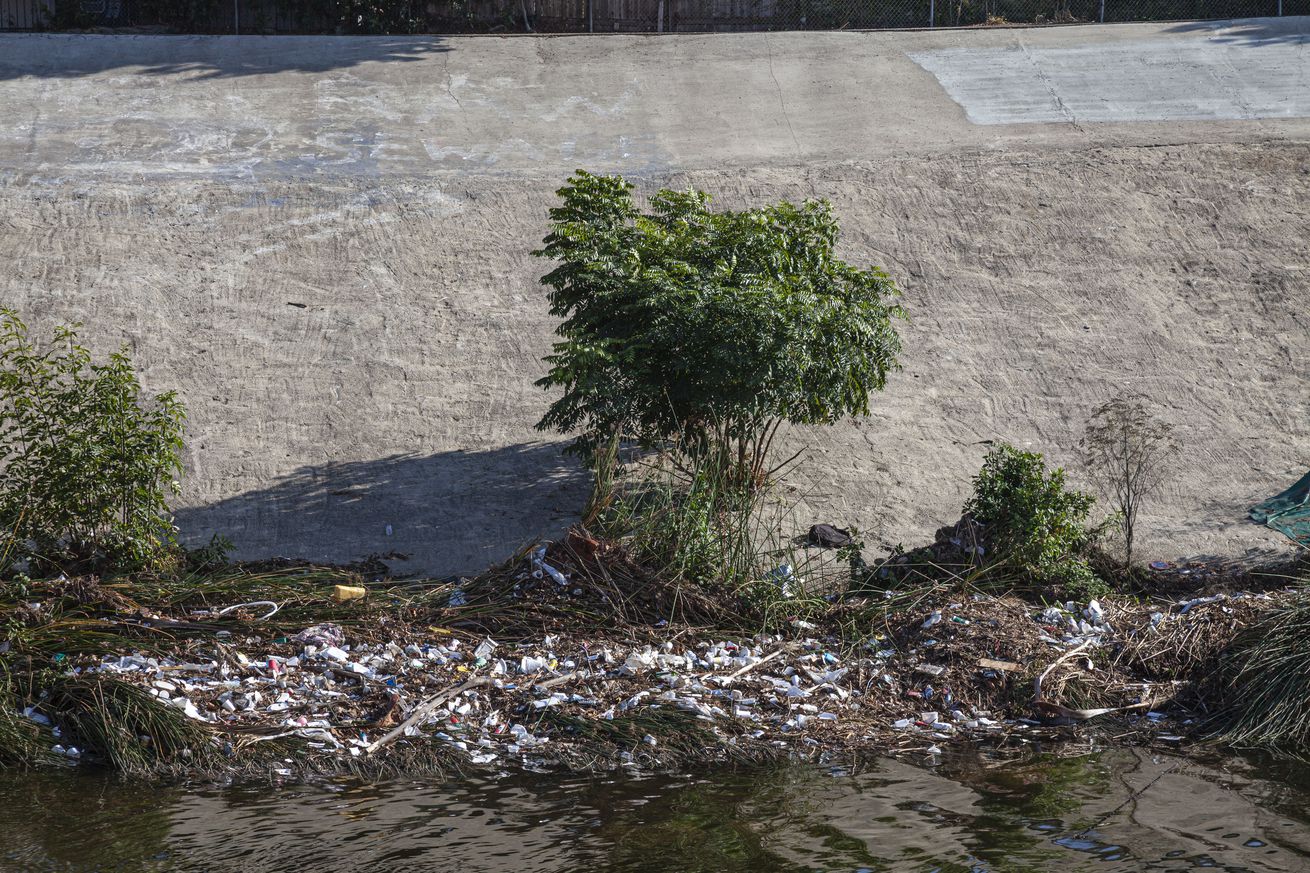 piles of plastic litter along the banks of a creek