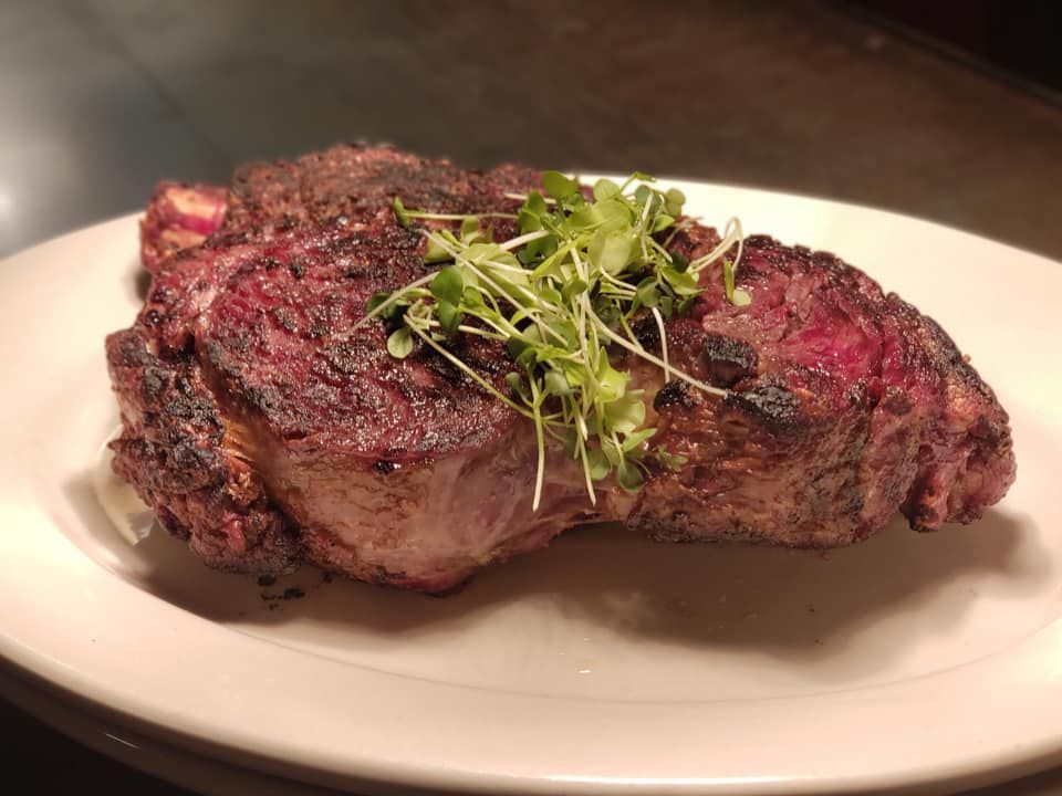 A huge piece of steak on an oval plate with a sprinkling of herbs on top