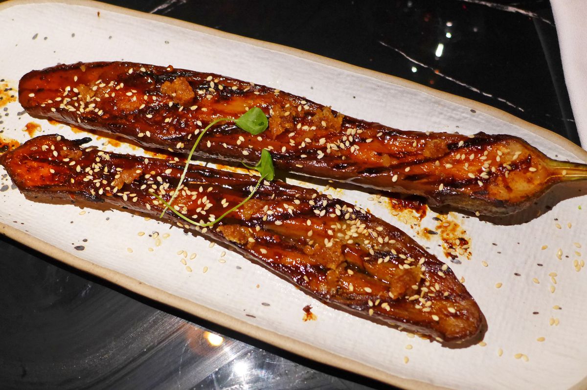 Two long and slend eggplant halves sprinkled with sesame seeds.