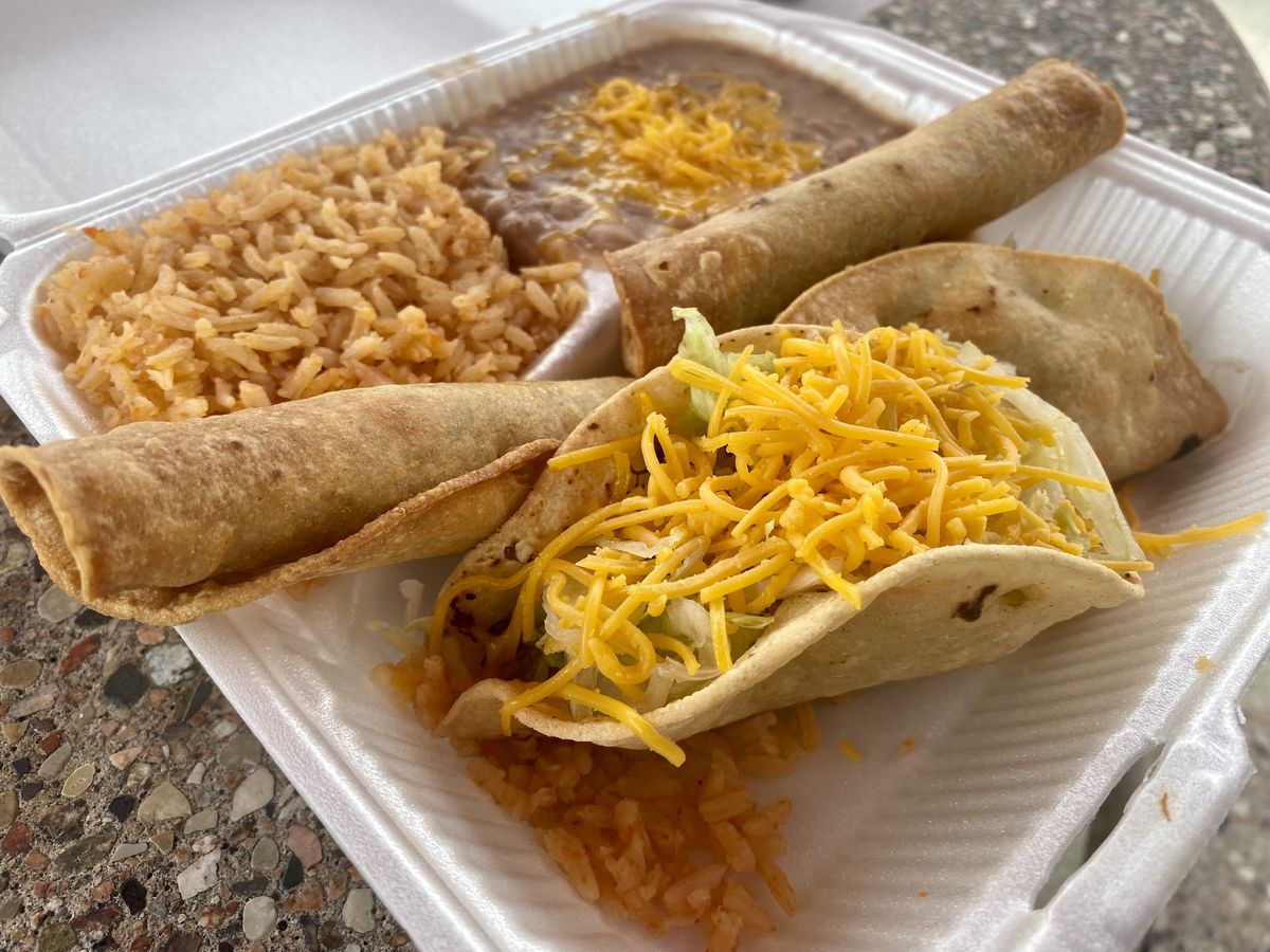 Tacos, flautas, beans, and rice in a styrofoam takeout container.