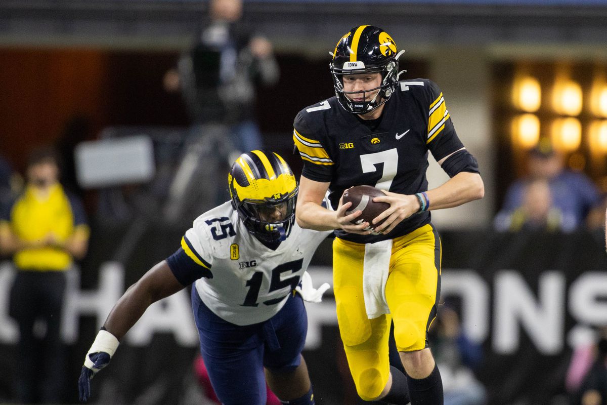 Iowa Hawkeyes quarterback Spencer Petras runs the ball while Michigan Wolverines defensive lineman Christopher Hinton defends in the second quarter at Lucas Oil Stadium.