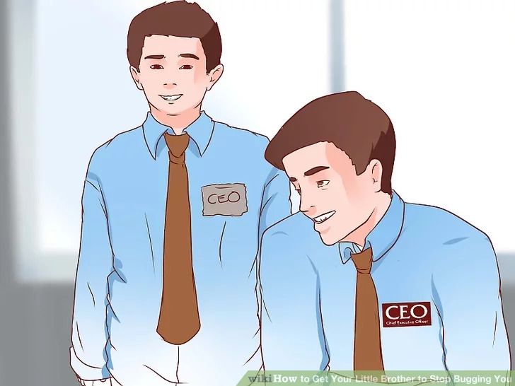 Image of two people, both wearing blue shirts and brown ties. The person on the right is sitting down. He has a red name tag that says “CEO” on it. He’s looking over at a younger person on his left. The younger person is wearing a handwritten name tag that says, “CEO”.