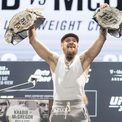 Conor McGregor poses with both belts at UFC 229 press conference.