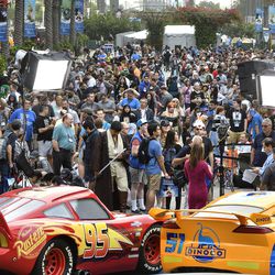 A crowd of people wait to enter the D23 Expo as crews do interviews outside the Anaheim Convention Center in Anaheim, Calif., on Friday, July 14, 2017.