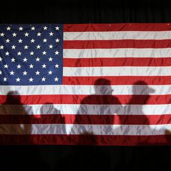 Supporters of Republican presidential candidate Ted Cruz cast shadows on an American flag during a "Women for Cruz" event with Cruz in Madison, Wis. Wednesday, March 30, 2016. 