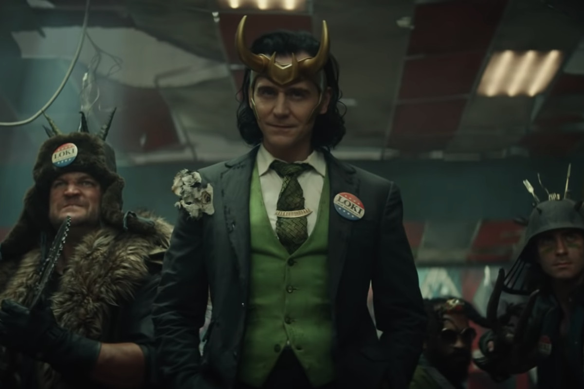 Tom Hiddleston as Loki, dressed in a ragged suit with a VOTE LOKI lapel pin, in Loki (Disney Plus)
