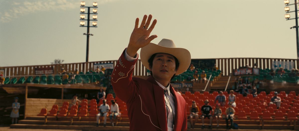 Ricky “Jupe” Park (Steven Yeun), vestido con un traje de vaquero y sosteniendo su mano derecha, en Nope