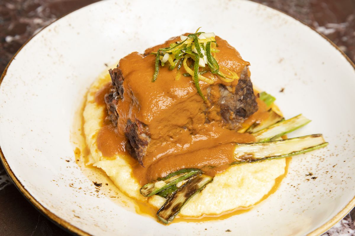 A plate of braised short ribs with sauce.