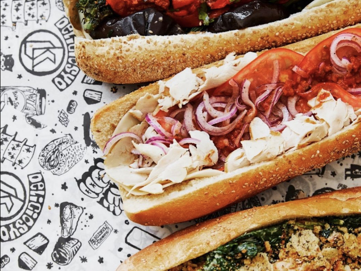 Three different hoagies dressed up with various meats, cheeses, and vegetables. 