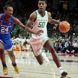 Oregon forward Eric Williams Jr., right, dribbles around BYU forward Seneca Knight during the first half of an NCAA college basketball game in Portland, Ore., Tuesday, Nov. 16, 2021.