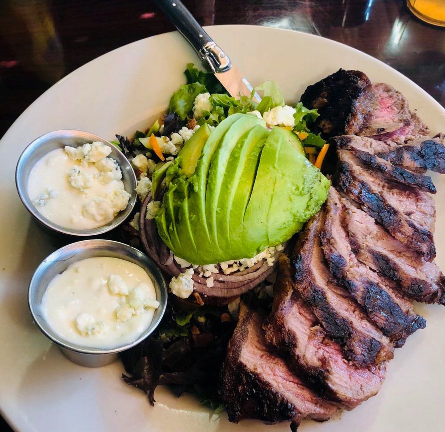 A steak salad with an avocado slice in the middle