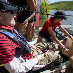 Members of Tetradapt Initiative help secure Derek Sundquist into an adaptive sailboat at East Canyon Reservoir in East Canyon State Park on Thursday, July 18, 2019. The sailboat is equipped with technology that allows Sundquist, a quadriplegic, to control the speed and direction of the craft with blows and sucks through a straw.
