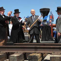 President Russell M. Nelson of The Church of Jesus Christ of Latter-day Saints, center, hoists his hammer after driving the "Utah copper spike" during the 150th anniversary celebration of the transcontinental railroad at the Golden Spike National Historical Park at Promontory Summit on Friday, May 10, 2019.