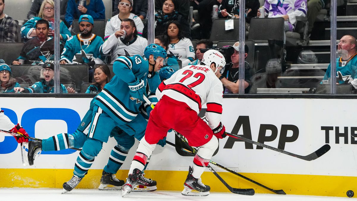 Nick Bonino #13 of the San Jose Sharks fights for the puck from Brett Pesce #22 of the Carolina Hurricanes at SAP Center on October 14, 2022 in San Jose, California.