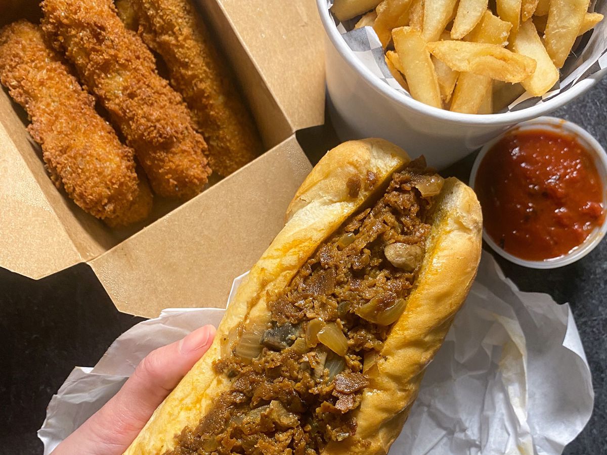 A photo of a vegan Philly cheesesteak, mozzarella sticks, and fries from Buddy’s Steaks