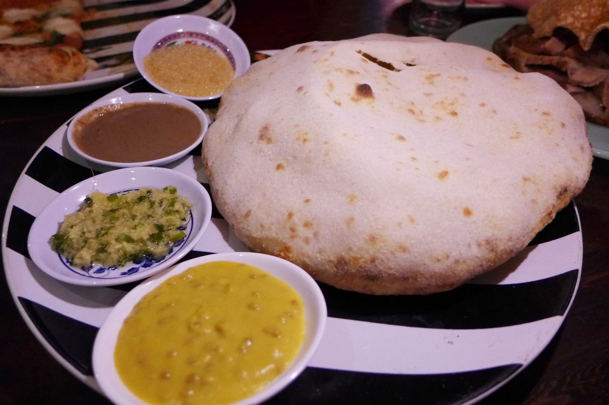 A puffy round flatbread with four dips.