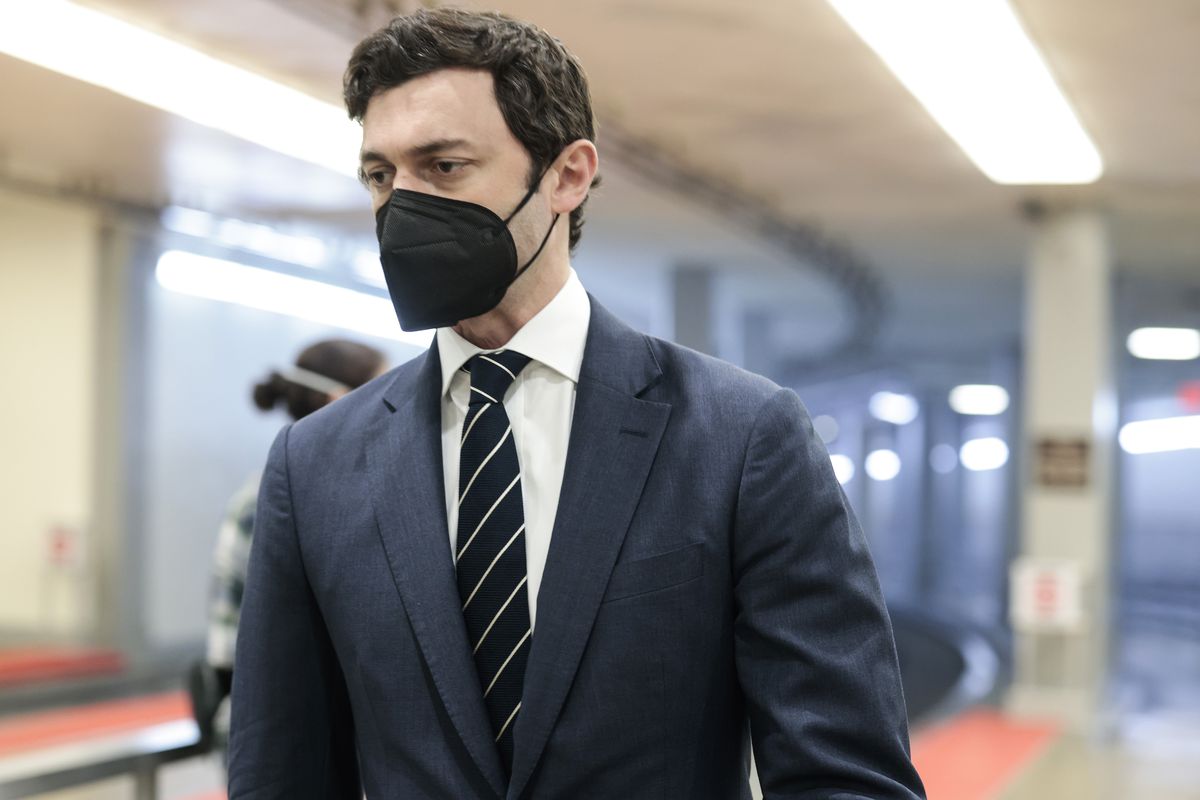Sen. Jon Ossoff, wearing a black face mask and a dark tie, walks through the Senate subway in the US Capitol during a vote on December 6, 2021.