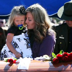 Christy Ivie, wife of U.S. Border Patrol agent Nicholas J. Ivie helps her 3-year-old daughter, Raigan, place a flower on the casket of her husband at the end of a graveside ceremony in Spanish Fork, Thursday, Oct. 11, 2012.