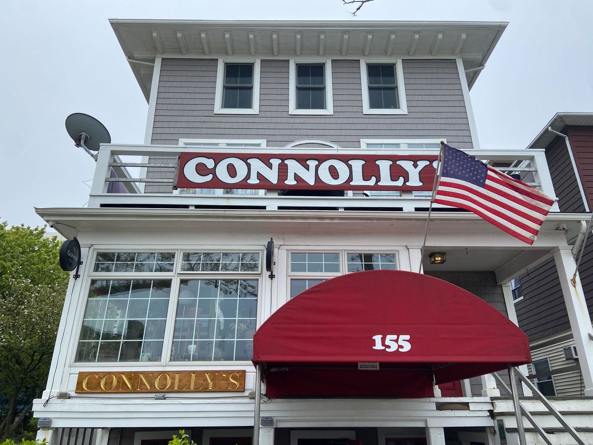 A red awning on a wood-laden building front says the Connolly’s name and also boasts an extending American flag.