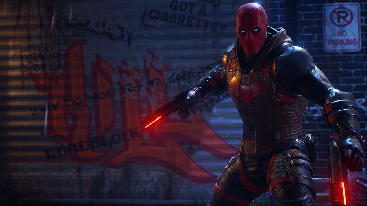 Red Hood stands in front of a shop gate in Gotham Knights.