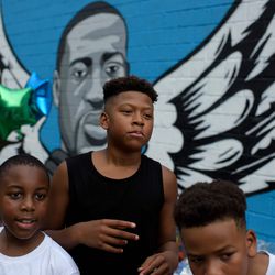 A group of boys poses next to a mural of George Floyd during a block party celebrating Juneteenth outside of the Scott Food Mart on June 19, 2020 in Houston, Texas.