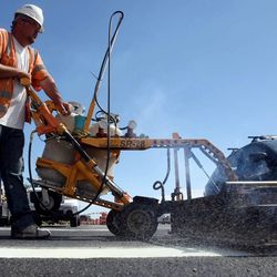Nick Martinez heats thermoplastic road markings with a burning machine on 400 South in Salt Lake City on Friday, June 21, 2013.