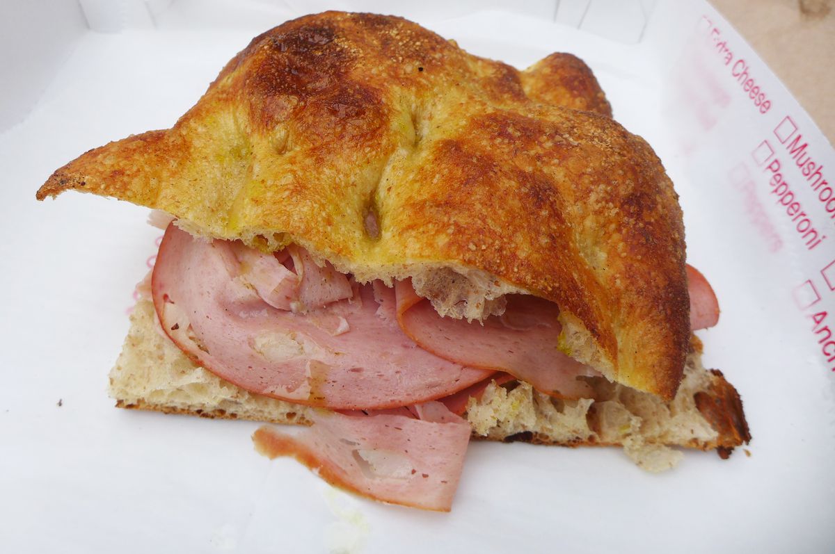 A focaccia split horizontally and carelessly stuffed with a few slices of mortadella.
