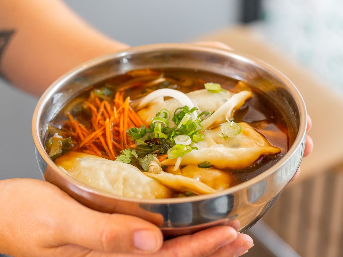 person holding bowl with dumpling soup