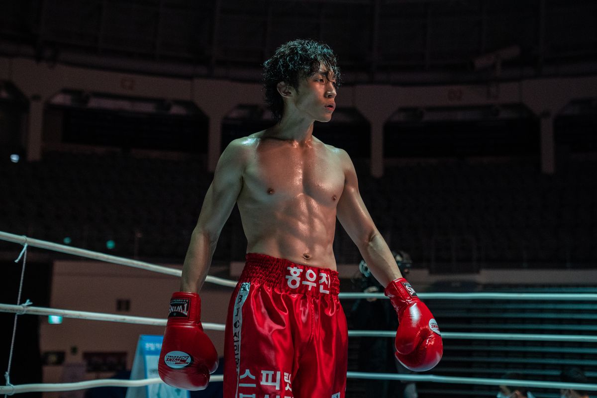 Hong Woo-jin struts in the boxing ring wearing red trunks and red gloves in Bloodhounds.