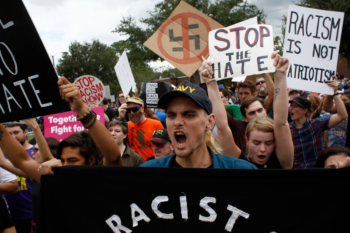 Counter-protesters at a white nationalist rally hold up signs that say “Stop the Hate” and “Racism is not Patriotism”