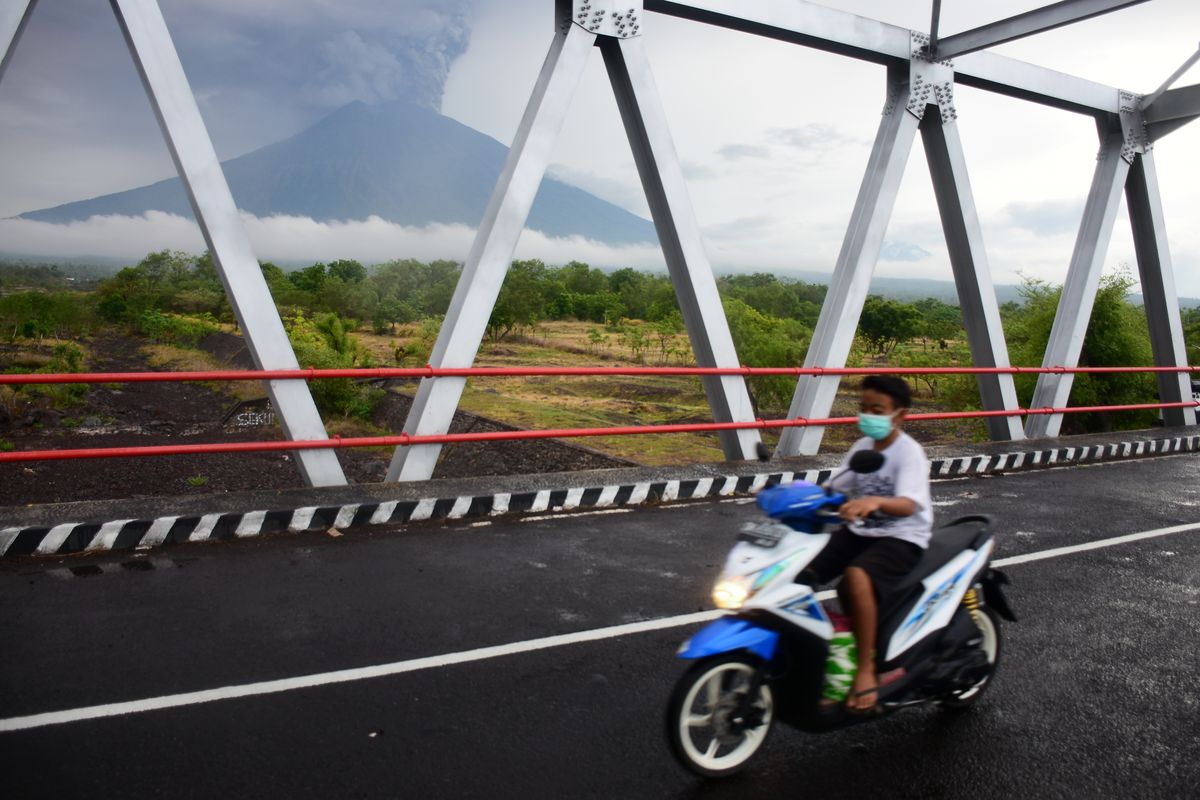 A man riding a motorcycle, crossing a bridge on Jl. Kubu, Karangasem, Bali on 27 November 2017, when the phreatic eruption of Mount Agung happened. (Photo by Keyza Widiatmika/NurPhoto via Getty Images)