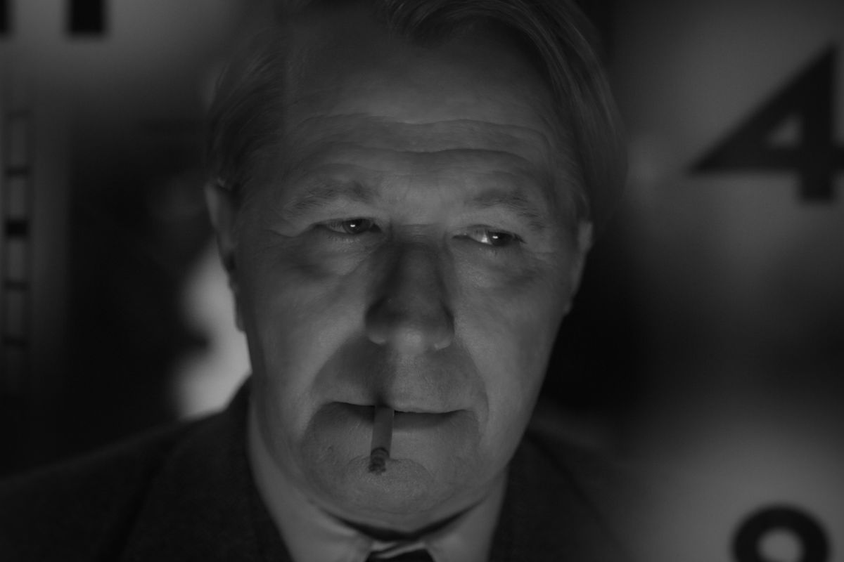 A man smokes a cigarette in black and white.