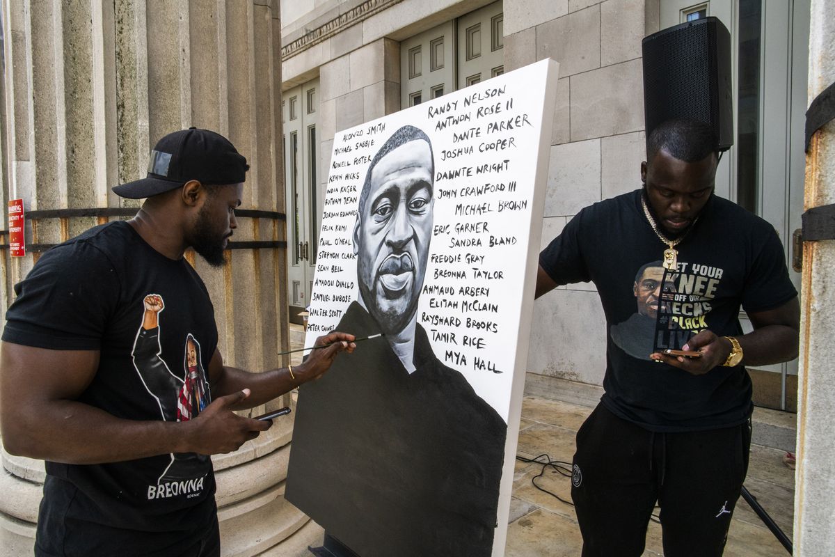 Artist Dennis Owes, 31, from Ghana gives the last touch to his portrait of George Floyd during a rally on Sunday, May 23, 2021, in Brooklyn borough of New York. 